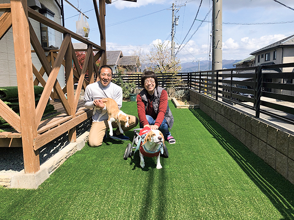 人工芝の上で笑顔の御夫婦とワンちゃん