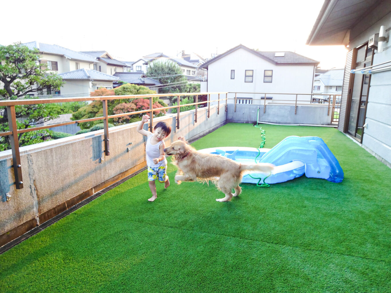 人工芝の庭で遊ぶ子どもと犬
