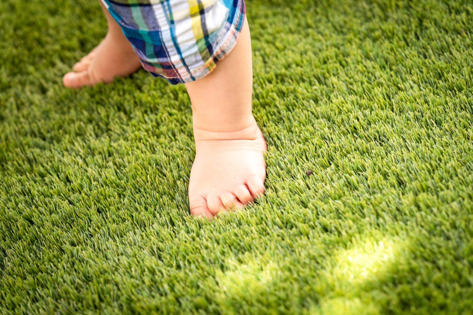 人工芝に裸足で乗る赤ちゃんの足