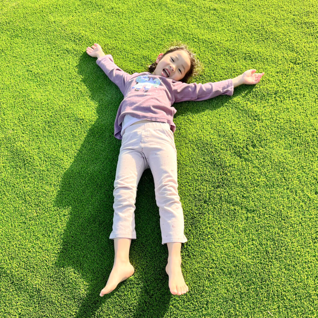 人工芝の上で仰向けに寝転がる女の子