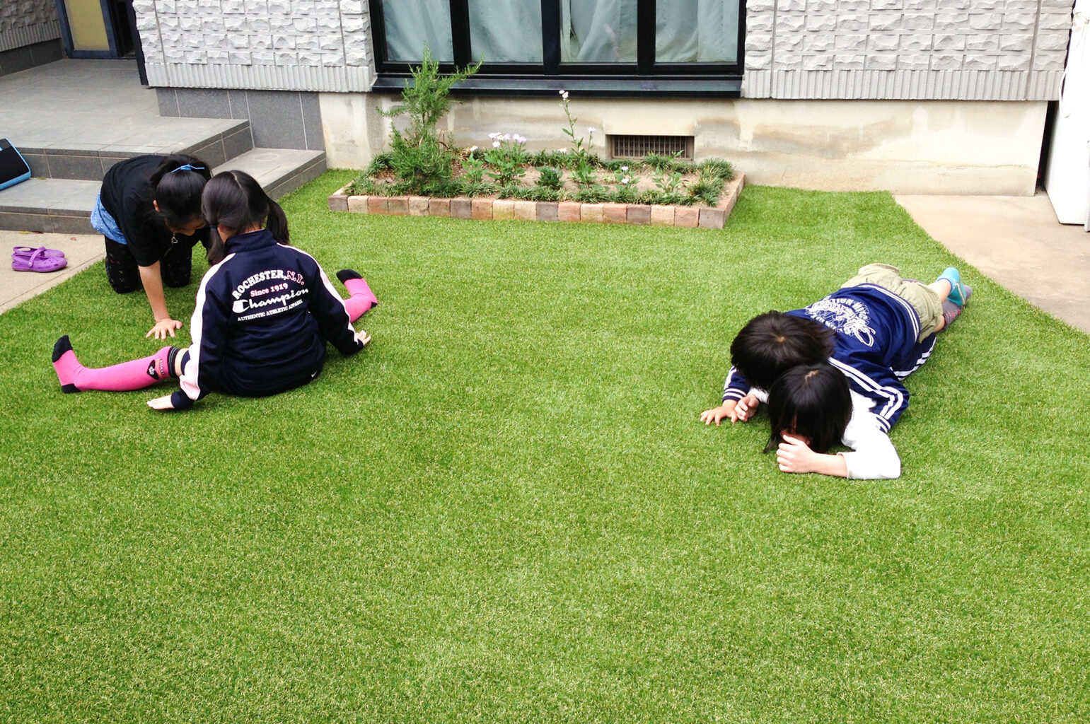 人工芝の庭で寝転ぶ子どもたち