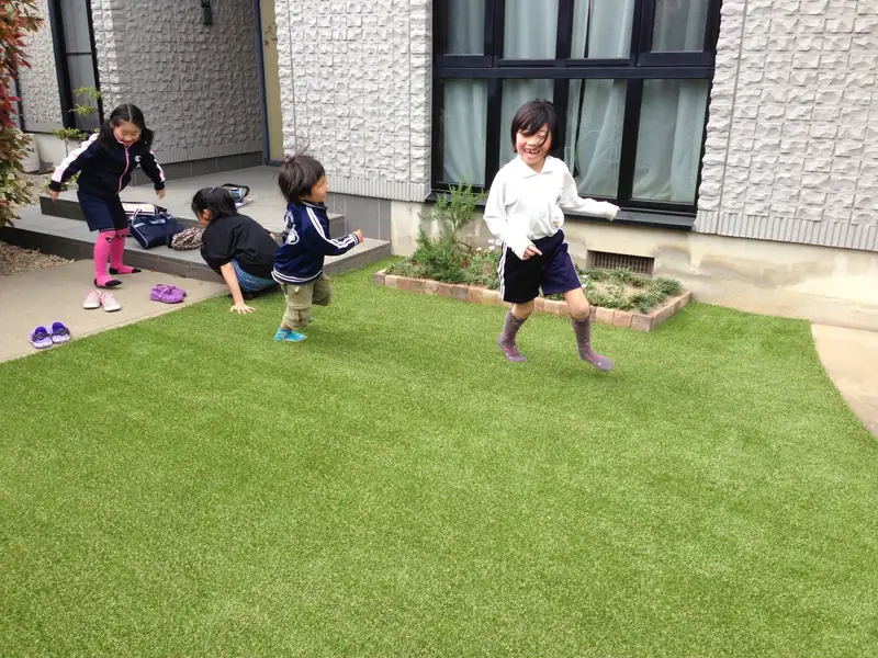 人工芝を敷いた庭で走り回る子どもたち